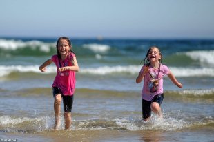 Summer fun: Sisters Sophie Wenman, nine, and Hannah Wenman, seven, are seen playing in the sea on a beach in Lossiemouth, Scotland
